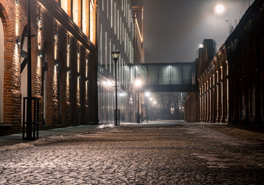 Foggy cobblestone street in an old European town at night with a single lit street lamp